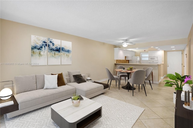 living room featuring ceiling fan, light tile patterned floors, and a textured ceiling