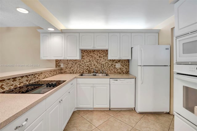 kitchen featuring white appliances, backsplash, white cabinetry, and sink