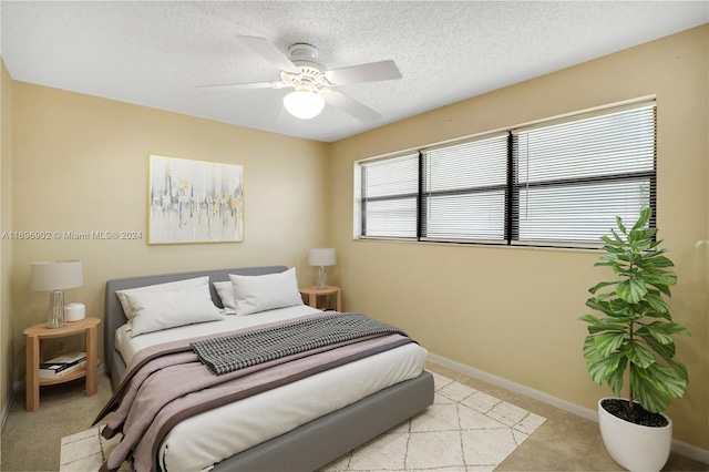 carpeted bedroom with ceiling fan and a textured ceiling