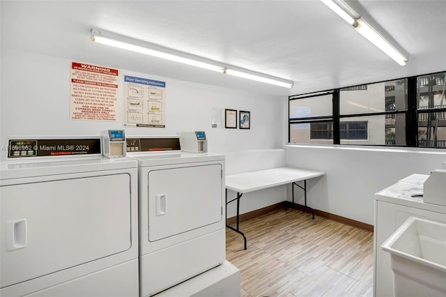 clothes washing area featuring light wood-type flooring, separate washer and dryer, and sink