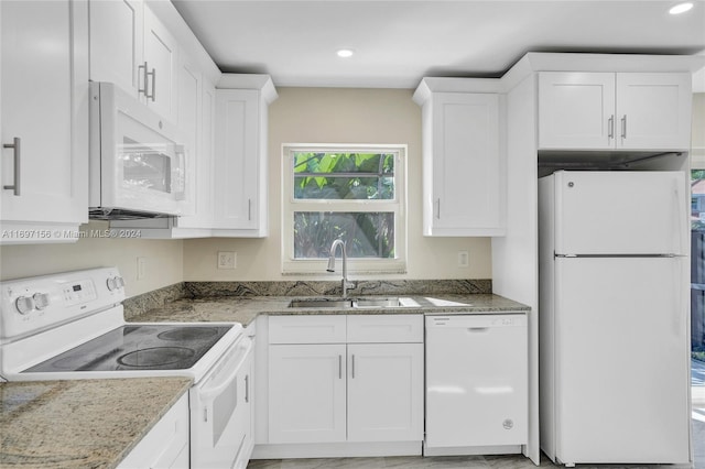 kitchen with stone countertops, white cabinetry, white appliances, and sink