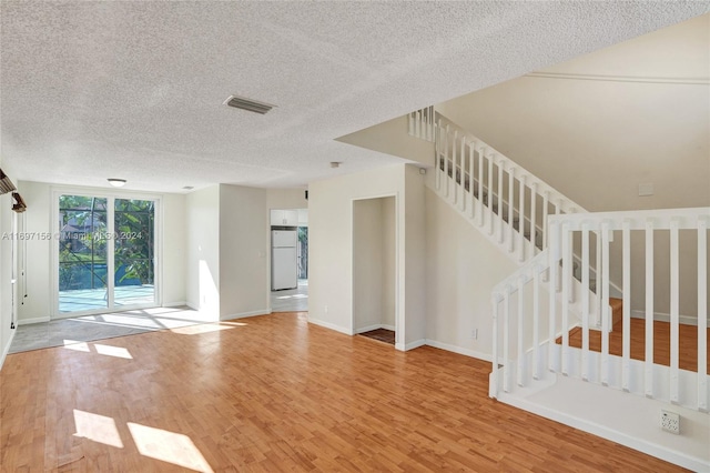 unfurnished room with a textured ceiling and light hardwood / wood-style floors