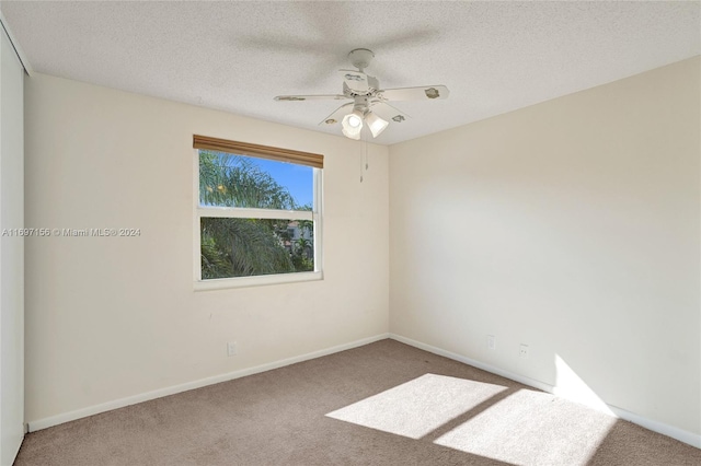 carpeted empty room with ceiling fan and a textured ceiling