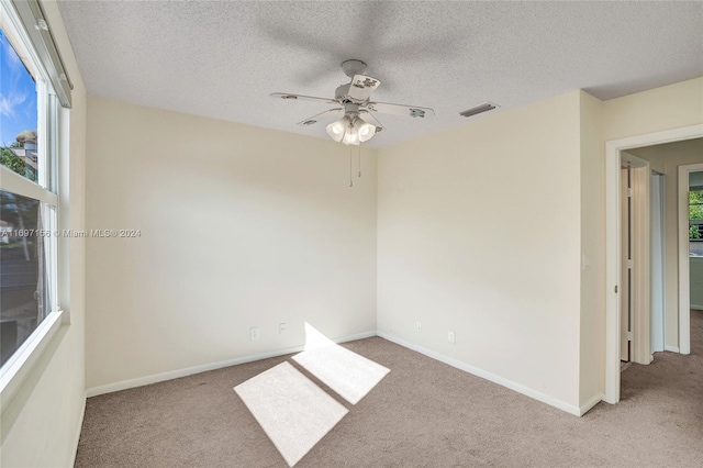 unfurnished room featuring a textured ceiling, ceiling fan, and light carpet