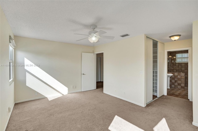 carpeted spare room featuring ceiling fan and a textured ceiling