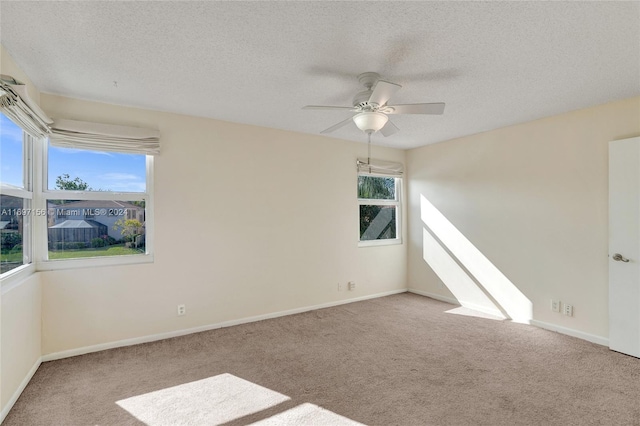 carpeted empty room featuring a textured ceiling, a wealth of natural light, and ceiling fan