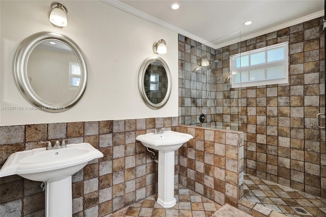 bathroom featuring tiled shower, tile walls, crown molding, and dual sinks