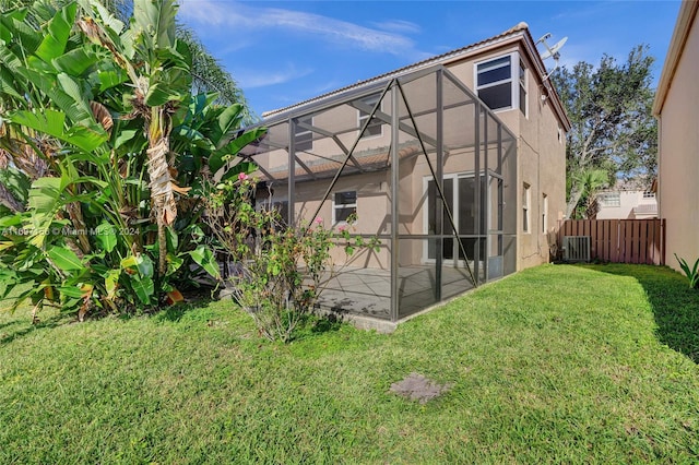 rear view of property with glass enclosure, a yard, and central AC