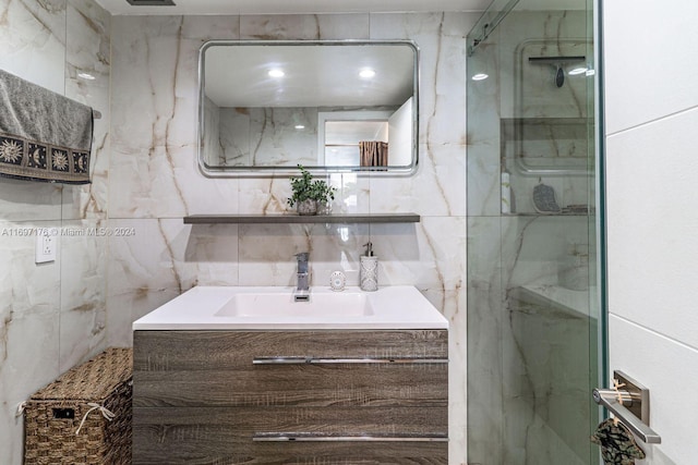 bathroom with vanity, tiled shower, and tile walls