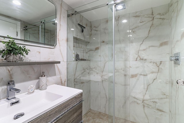 bathroom with vanity, a shower with door, and tile walls