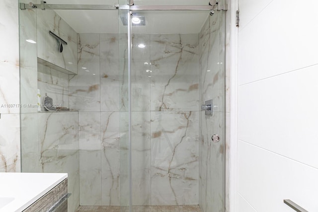 bathroom featuring a shower with door and vanity