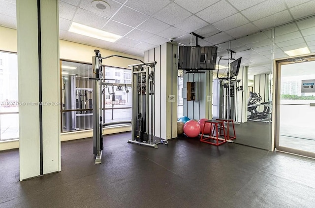 exercise room featuring a drop ceiling and a healthy amount of sunlight