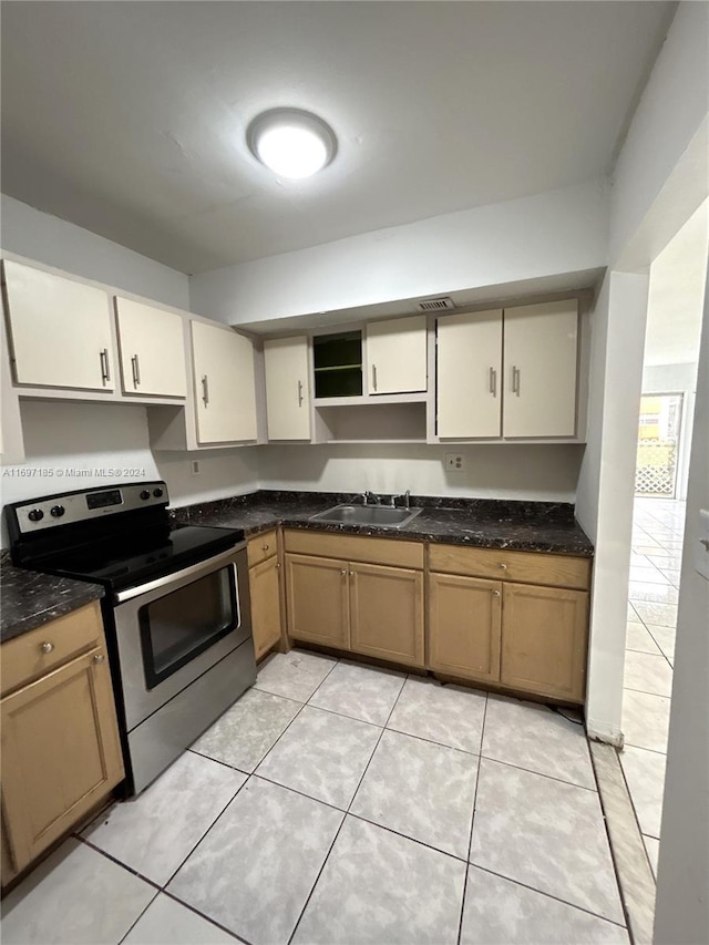 kitchen with light tile patterned floors, stainless steel range with electric stovetop, dark stone counters, and sink