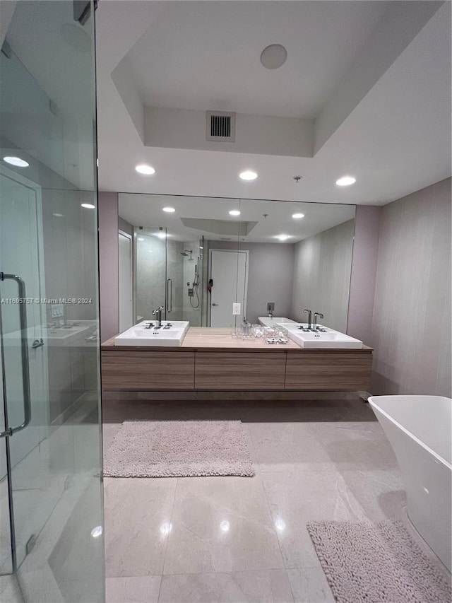 bathroom featuring a tray ceiling, vanity, and shower with separate bathtub