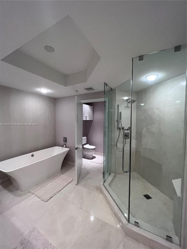 bathroom featuring a raised ceiling and separate shower and tub