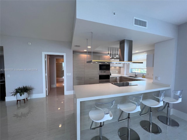 kitchen with a kitchen bar, kitchen peninsula, island range hood, black electric cooktop, and sink