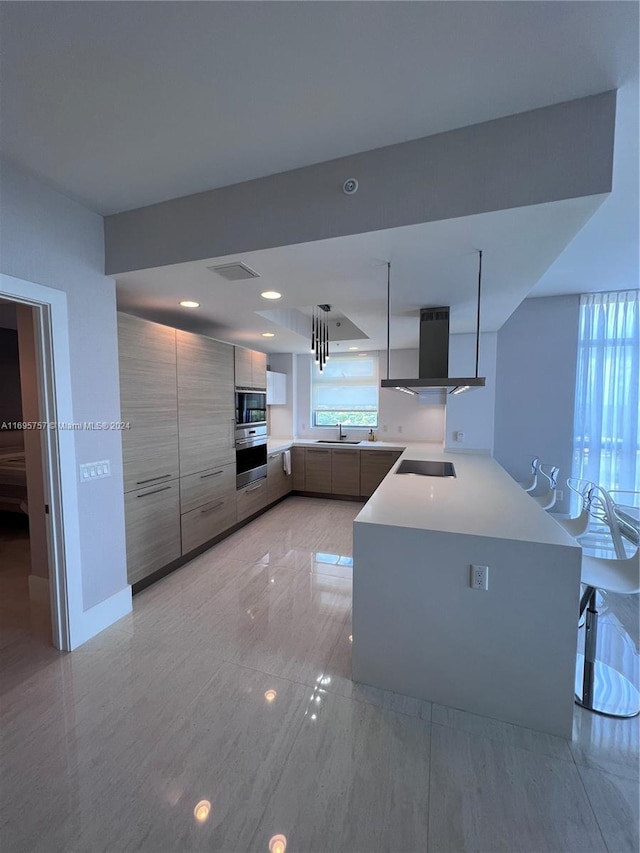 kitchen with stainless steel appliances, wall chimney range hood, kitchen peninsula, decorative light fixtures, and a kitchen bar