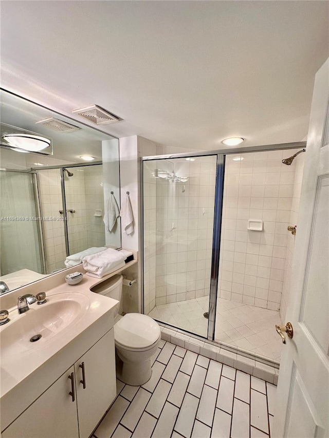 bathroom featuring tile patterned flooring, vanity, toilet, and an enclosed shower