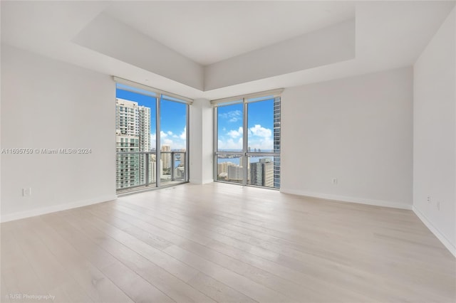 1060 Brickell Ave Unit 4101, Miami, FL 33131 - spare room with a tray ceiling, light wood-style floors, baseboards, and expansive windows