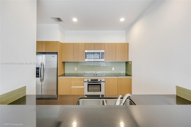 kitchen with appliances with stainless steel finishes, backsplash, and light brown cabinets