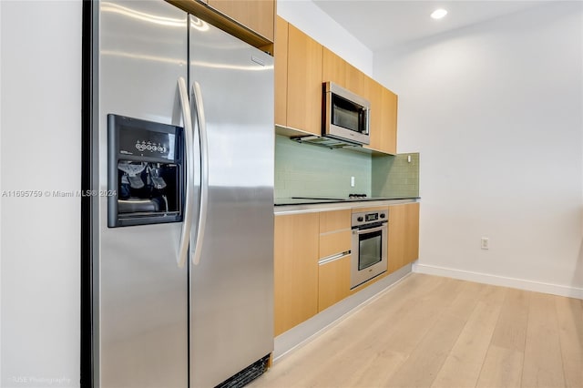 1060 Brickell Ave Unit 4101, Miami, FL 33131 - kitchen featuring appliances with stainless steel finishes, modern cabinets, backsplash, light wood-type flooring, and light brown cabinetry