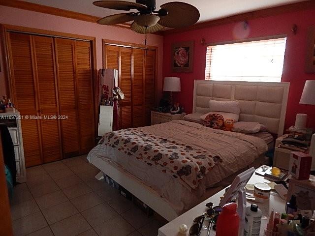 bedroom featuring tile patterned flooring, ceiling fan, and multiple closets