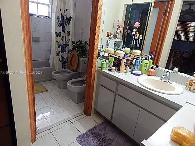 full bathroom with vanity, a bidet, tile patterned floors, toilet, and shower / bath combo with shower curtain