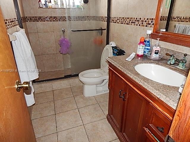 bathroom with vanity, radiator, tile patterned flooring, toilet, and tile walls