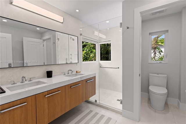 bathroom featuring tile patterned flooring, vanity, toilet, and a shower with door