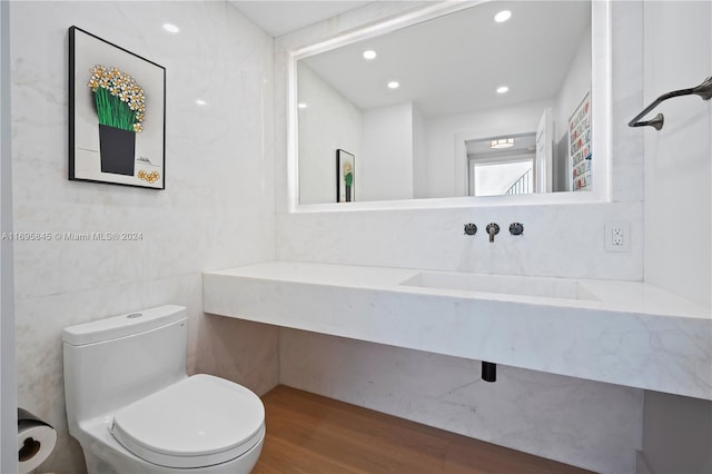 bathroom featuring sink, wood-type flooring, tile walls, and toilet