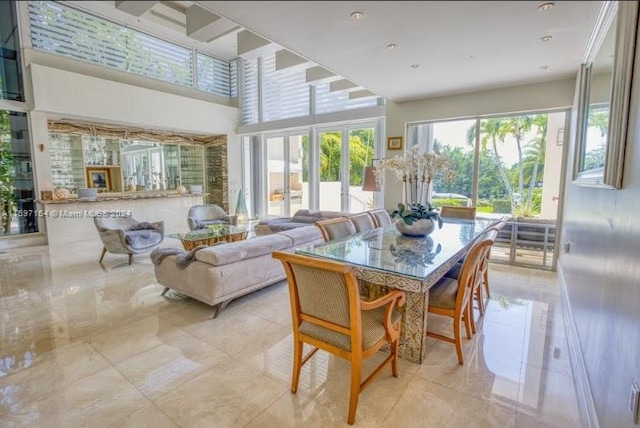 dining area with a towering ceiling and light tile patterned floors