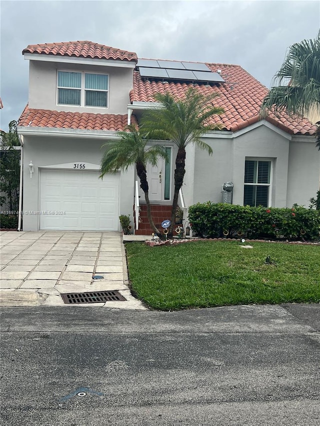 mediterranean / spanish home featuring a front yard, solar panels, and a garage