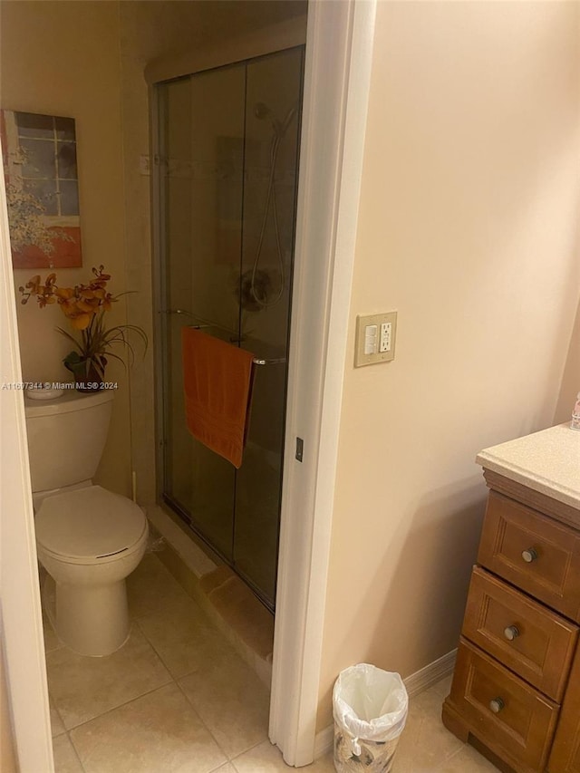 bathroom with tile patterned floors, vanity, an enclosed shower, and toilet