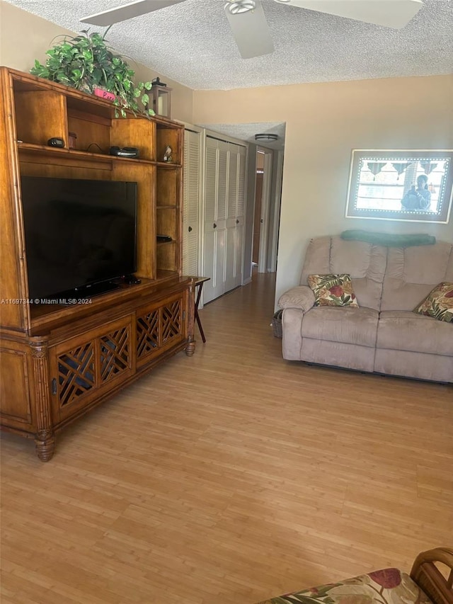 living room featuring ceiling fan, a textured ceiling, and light hardwood / wood-style flooring