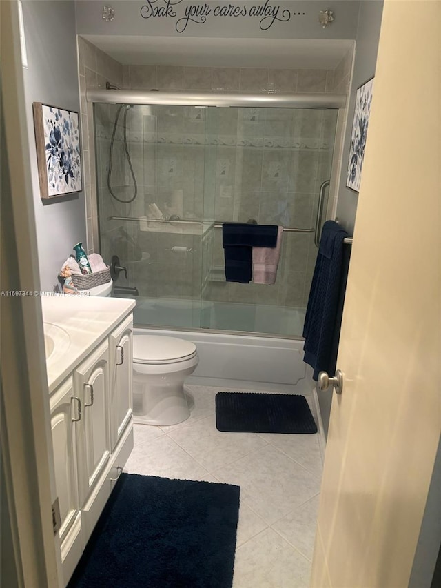 full bathroom with toilet, vanity, tile patterned floors, and bath / shower combo with glass door