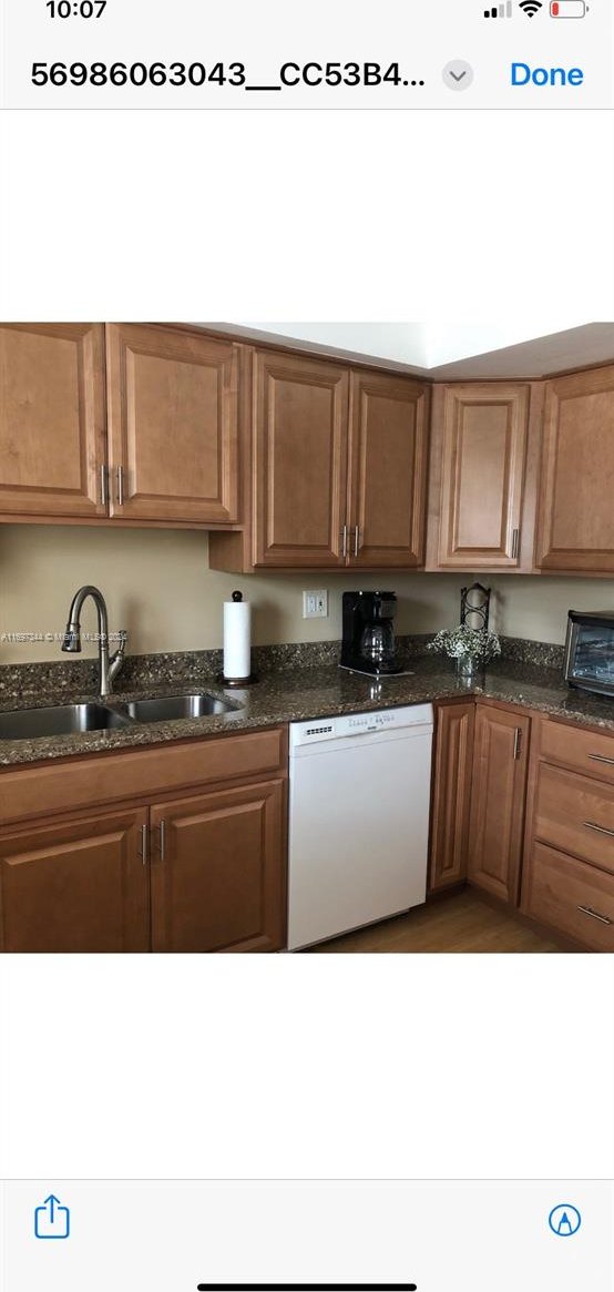 kitchen featuring dishwasher, dark stone countertops, and sink