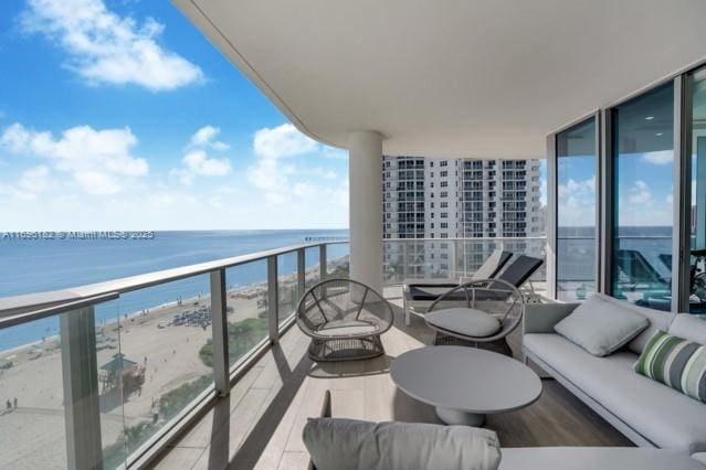 balcony featuring an outdoor living space, a water view, and a beach view