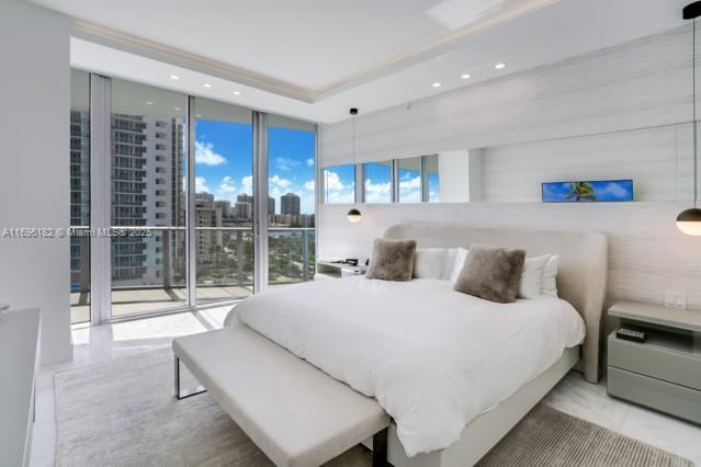 bedroom featuring a raised ceiling, a wall of windows, and access to outside