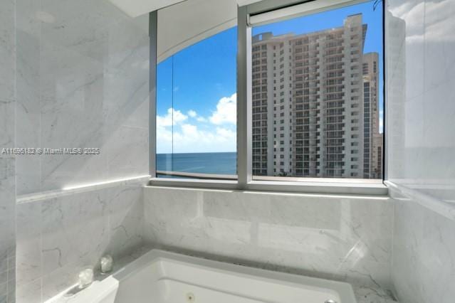 bathroom with a washtub, a water view, and a wealth of natural light