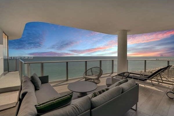 balcony at dusk featuring outdoor lounge area and a water view