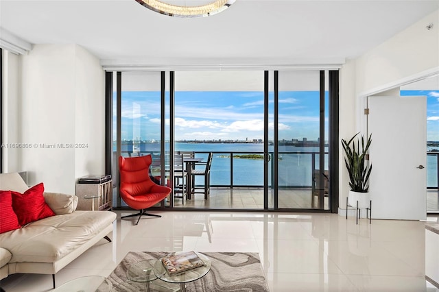 living room featuring tile patterned flooring, a water view, and a wall of windows