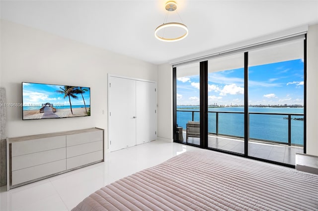 unfurnished bedroom featuring access to exterior, a water view, a closet, and light tile patterned flooring