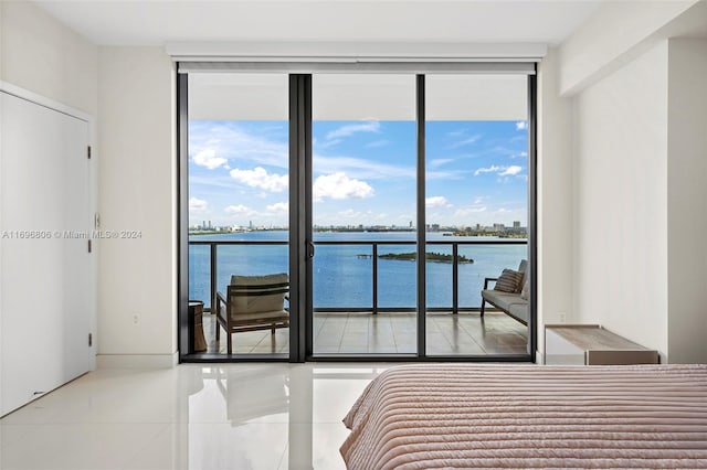 bedroom with access to outside, a water view, light tile patterned floors, and a wall of windows