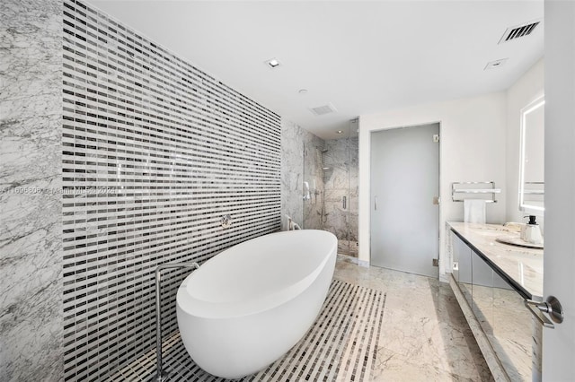 bathroom featuring vanity, separate shower and tub, and tile walls