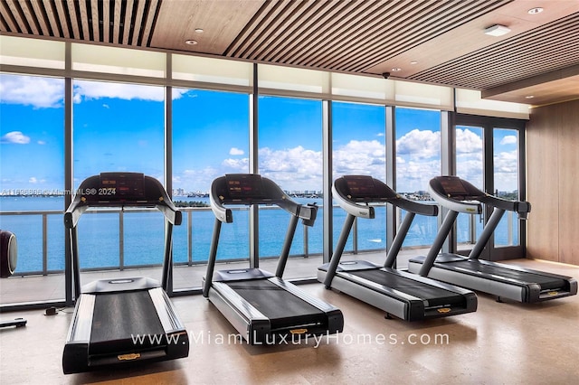 exercise room with expansive windows and a water view