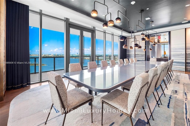 dining room featuring wood-type flooring, a water view, and floor to ceiling windows