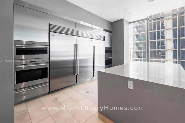 788 NE 23rd St Unit 2102, Miami, FL 33137 - kitchen with appliances with stainless steel finishes, a warming drawer, light tile patterned floors, and expansive windows