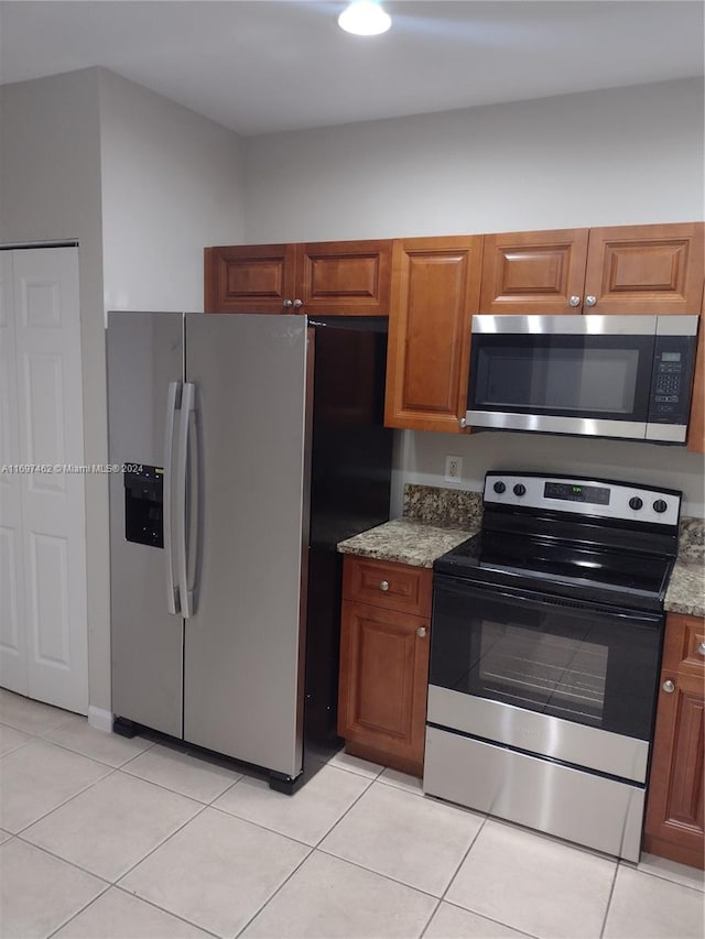 kitchen featuring light stone counters, light tile patterned floors, and stainless steel appliances