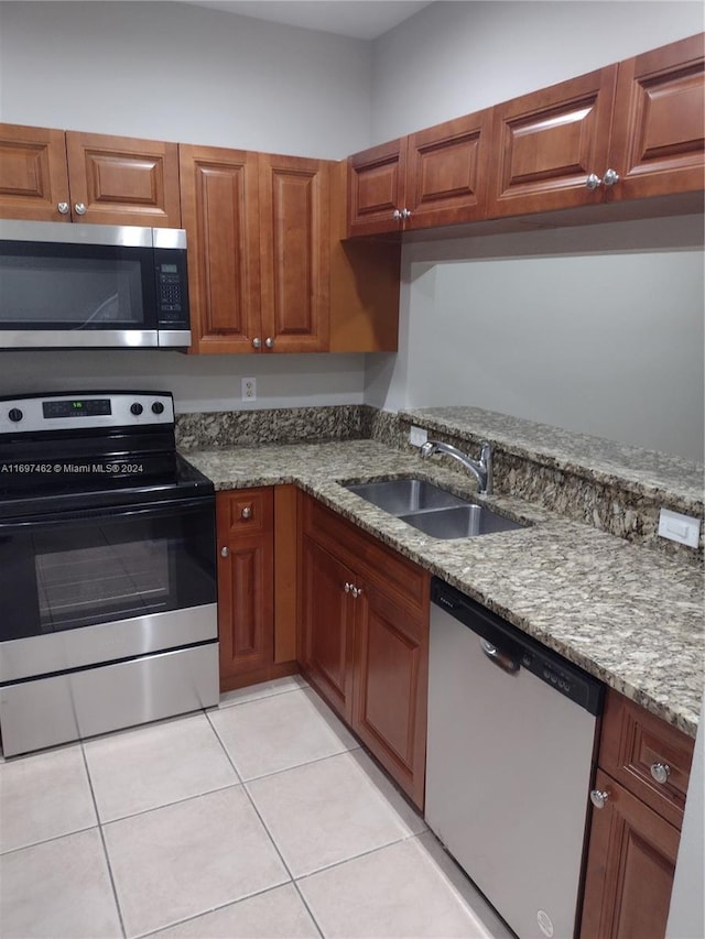 kitchen featuring stone counters, sink, light tile patterned flooring, and appliances with stainless steel finishes