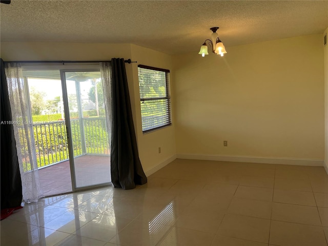 tiled empty room with a notable chandelier and a textured ceiling